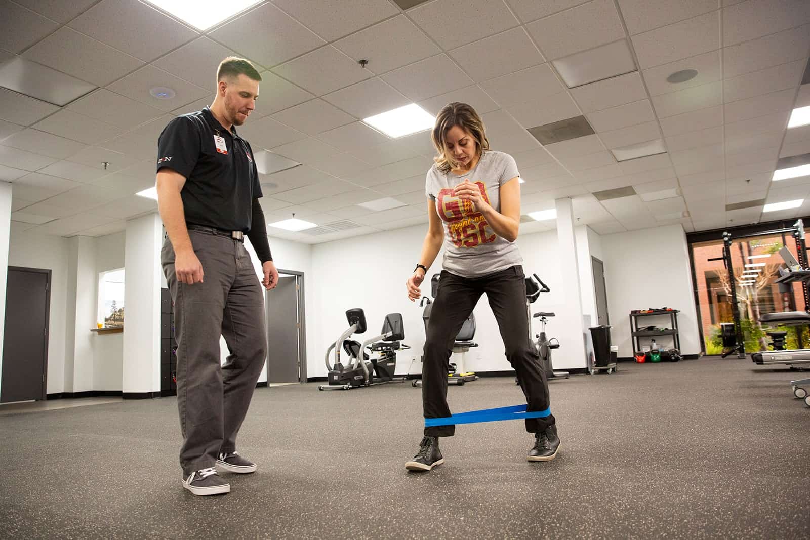 Physical therapy session with a therapist guiding a woman using resistance bands.