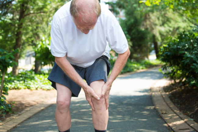 Man clutches his knee while on a run