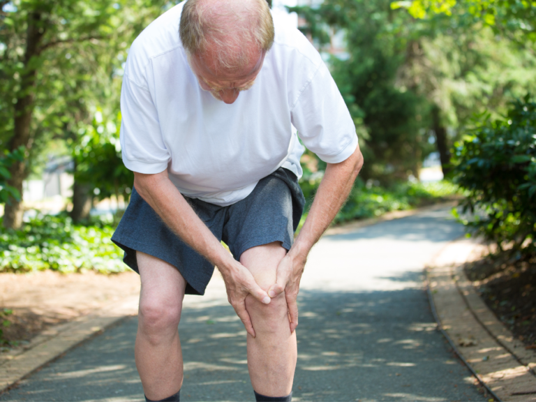 Man clutches his knee while on a run
