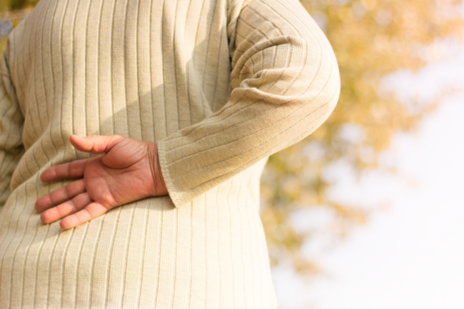 Woman holds her back to to lower back pain