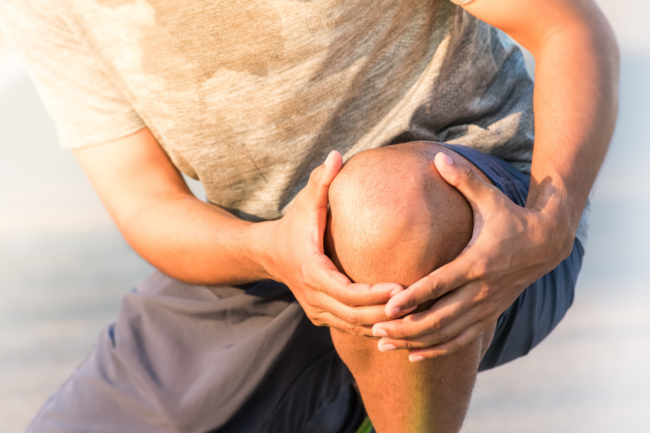 A runner holds his knee due to inner knee pain