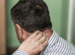 Man holds his neck due to pain requiring physical therapy