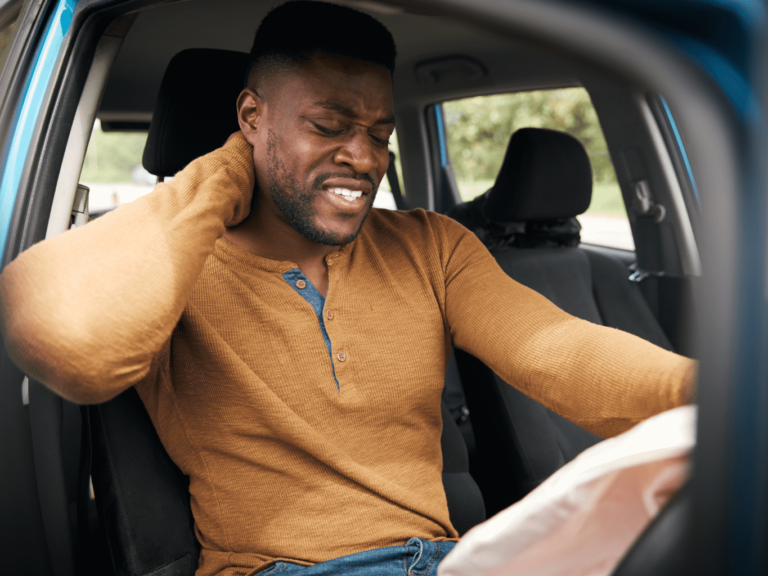 Man holds his neck after experiencing whiplash following a vehicle collision