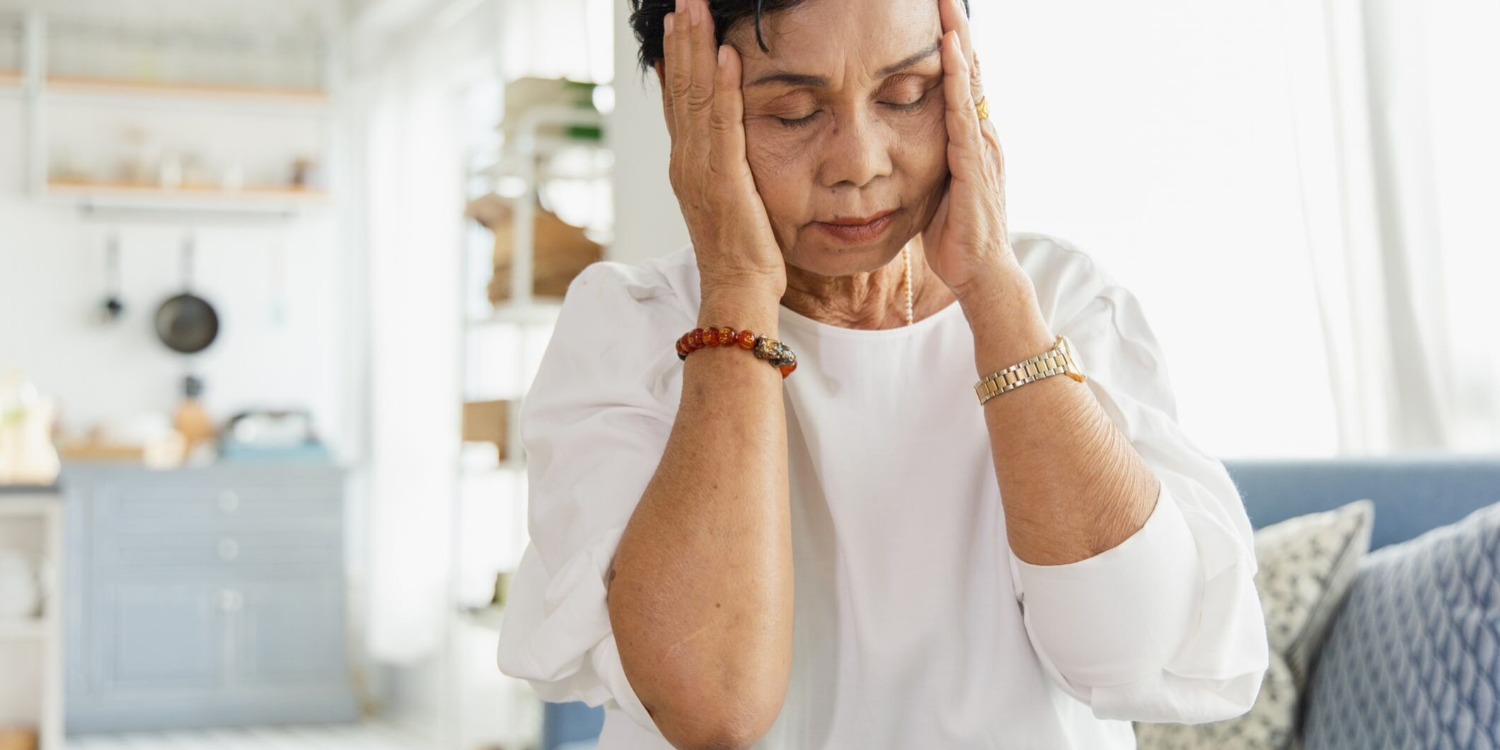 An elderly Asian woman uses her hand to grasp the head. Old women have dizziness and headache due to stress. She has a congenital disease. The health concept of retirement