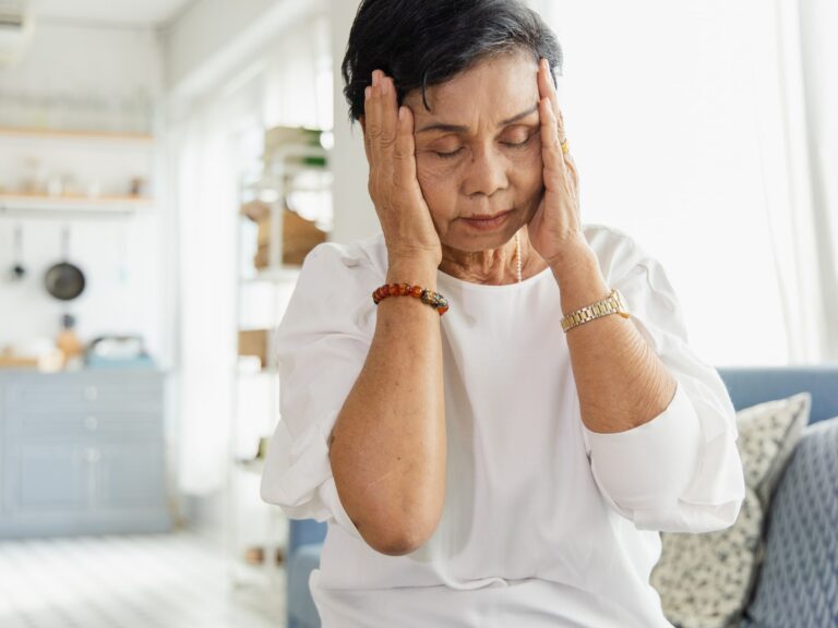 An elderly Asian woman uses her hand to grasp the head. Old women have dizziness and headache due to stress. She has a congenital disease. The health concept of retirement