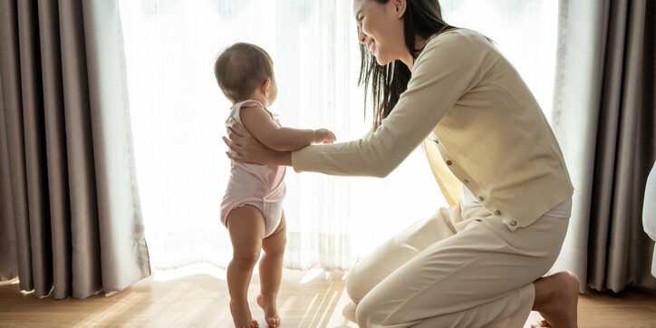 A baby girl learning first steps walk with mother, family, child, childhood and parenthood concept
