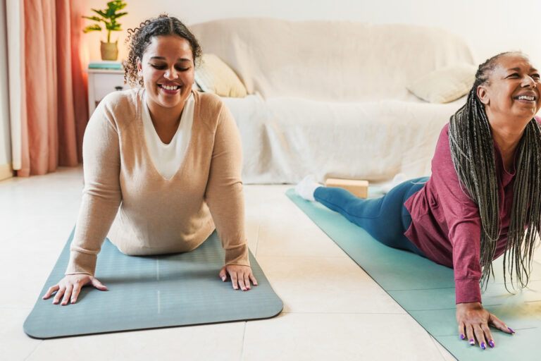 Mother and daughter doing yoga day routine at home together Family and sport concept during winter time Focus on girl face