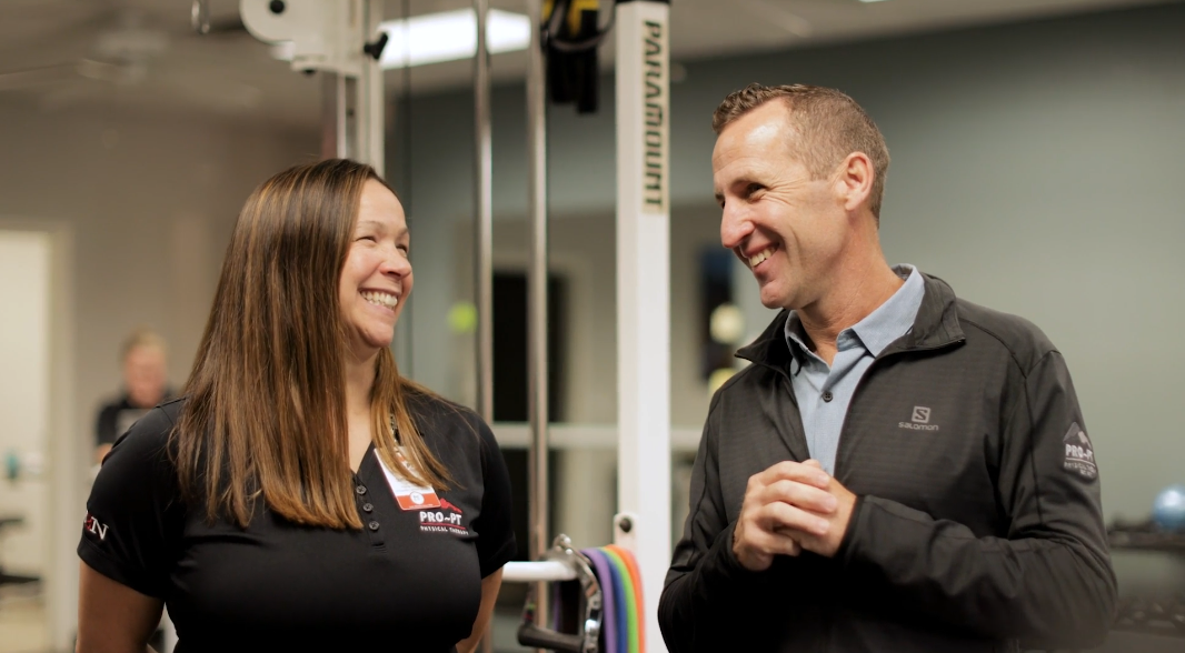 Two individuals having a conversation in a fitness center, sharing exercise tips and motivation.