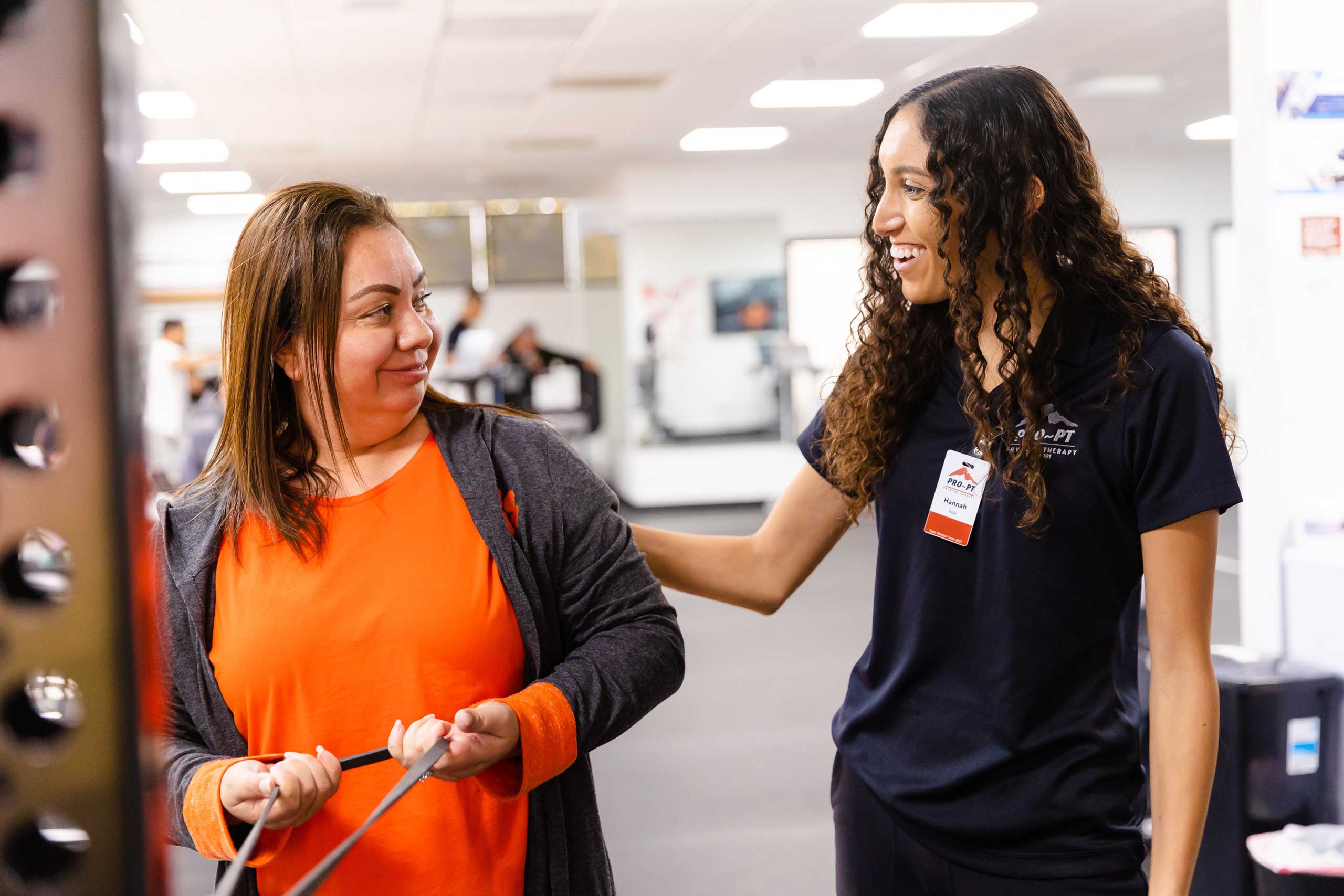 Physical therapist smiling and helping a client with cable exercises