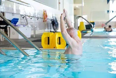 Swimming pool therapy session with a patient performing water exercises for rehabilitation.
